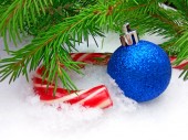 Modrá koule Silvestrovské a vánoční karamelové bonbóny s zelená jedle na zasněžené pozadí. Zavřít fotografie