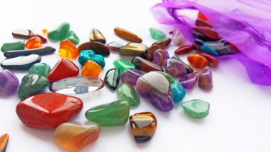 Çeşitli doğal parlak renkli yarı değerli taşlar ve çanta beyaz arka plan üzerinde mücevher