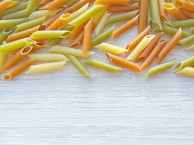 İtalyan yemeği arka plan - renkli pişmemiş penne makarna ahşap masa üzerine dokulu. Kopya alanı fotoğrafla kapatmak