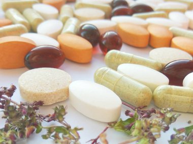 Beyaz arka planda kurumuş doğal bitkilerle birlikte bitkisel ilaç hapları. Bitkisel ilaç ve beslenme takviyesi kavramı, biyolojik olarak aktif katkı maddeleri ve vitaminler. Fotoğrafçılığı kapat