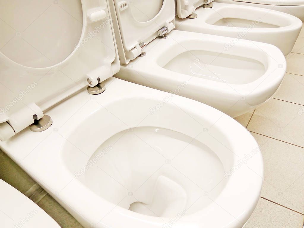 Group of new clean white opened toilet bowls in the store