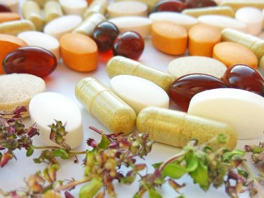 Beyaz arka planda kurumuş doğal bitkilerle birlikte bitkisel ilaç hapları. Bitkisel ilaç ve beslenme takviyesi kavramı, biyolojik olarak aktif katkı maddeleri ve vitaminler. Fotoğrafçılığı kapat