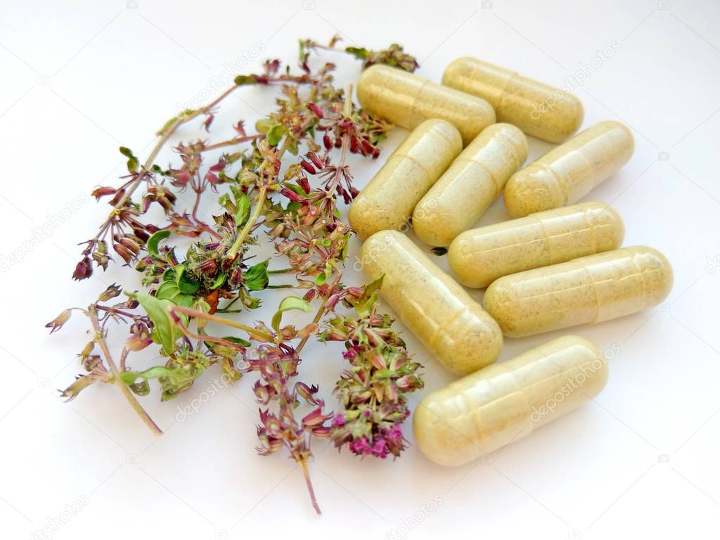 Herbal medicine pills with dry natural herbs on white background. Concept of herbal medicine and dietary supplements, biologically active additives and vitamins. Close up photography