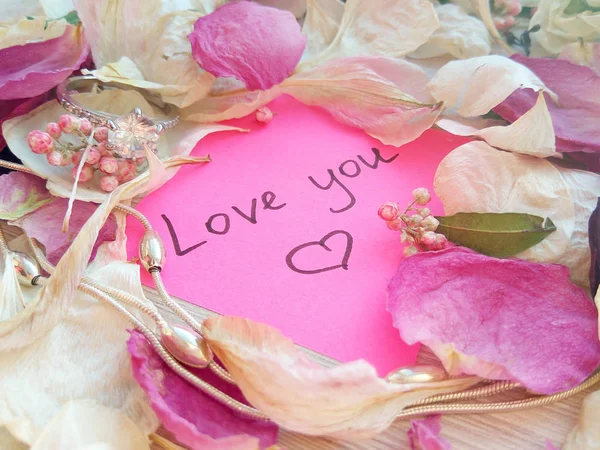 ドライのバラと蘭花の花弁 シルバージュ エリー リング ピンクの付箋上のメッセージと木製のテーブル背景にチェーンが大好き — ストック写真