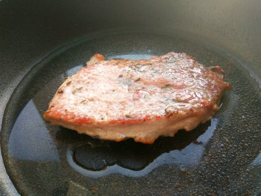 Siyah tava arka planda solt, biber, biberiye ve yağ ile organik pişmiş kızarmış domuz eti biftek et. Yakın çekim görünümü fotoğrafçılığı