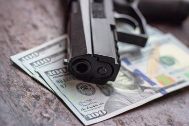Amerikan doları arka planında siyah silah. Askeri sanayi, savaş, küresel silah ticareti, silah satışı, sözleşmeli cinayet ve suç kavramı.