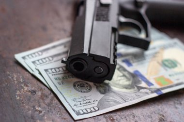 Amerikan doları arka planında siyah silah. Askeri sanayi, savaş, küresel silah ticareti, silah satışı, sözleşmeli cinayet ve suç kavramı