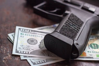 Amerikan doları arka planında siyah silah. Askeri sanayi, savaş, küresel silah ticareti, silah satışı, sözleşmeli cinayet ve suç kavramı
