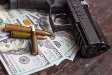Amerikan doları arka planında siyah silah ve silah mermileri var. Askeri sanayi, savaş, küresel silah ticareti ve suç kavramı.