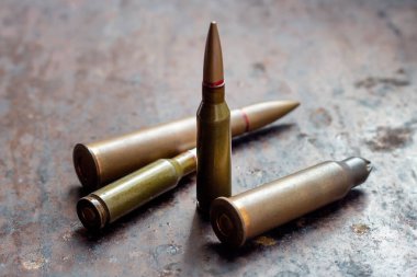 Paslı metal arka planda çeşitli silah mermileri. Askeri sanayi, savaş, küresel silah ticareti ve suç kavramı