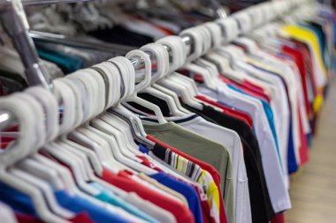 Perakende mağazasında bir asılı raf üzerinde birçok farklı renkli giysiler. Yumuşak seçici odak fotoğrafçılığı