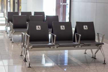 Engelliler için boş öncelikli kamu koltukları. Tekerlekli sandalyede engelli bir adamla beyaz tabela