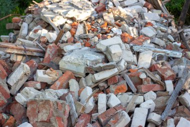 Uzak yeşil bir alanda inşaat çöp, enkaz ve atık moloz. Doğa ve toprak kirliliği konsepti