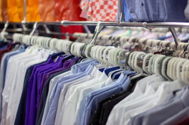 Perakende mağazasında bir asılı raf üzerinde birçok farklı renkli giysiler. Yumuşak seçici odak fotoğrafçılığı