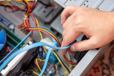 Genç teknisyen elindeki bilgisayarı onarmak için kabloyu tutuyor. Bilgisayar donanımı, servis, yükseltme ve teknoloji onarım konsepti