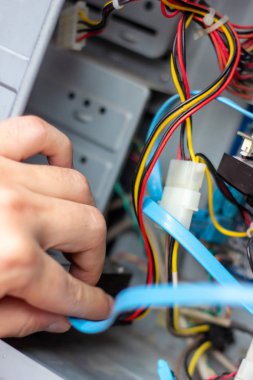 Genç teknisyen elindeki bilgisayarı onarmak için kabloyu tutuyor. Bilgisayar donanımı, servis, yükseltme ve teknoloji onarım konsepti