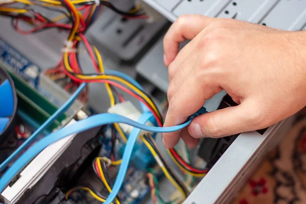 Genç teknisyen elindeki bilgisayarı onarmak için kabloyu tutuyor. Bilgisayar donanımı, servis, yükseltme ve teknoloji onarım konsepti