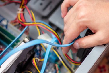 Genç teknisyen elindeki bilgisayarı onarmak için kabloyu tutuyor. Bilgisayar donanımı, servis, yükseltme ve teknoloji onarım konsepti.