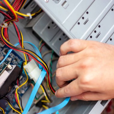 Genç teknisyen elindeki bilgisayarı onarmak için kabloyu tutuyor. Bilgisayar donanımı, servis, yükseltme ve teknoloji onarım konsepti.