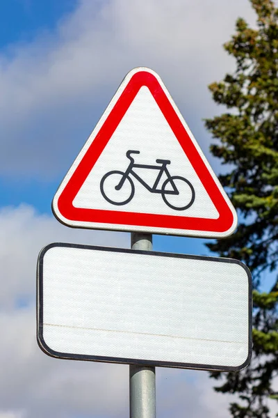 The red triangle sign prohibiting the entry of cyclists against the blue sky.