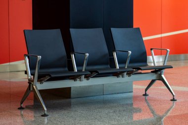 Havaalanındaki bekleme salonunda boş siyah koltuklar..