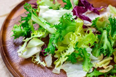 Çiğ organik salata yapraklarının farklı bir karışımı: marul, radicchio, ahşap tahtada roket hafif arka planda yemek için.