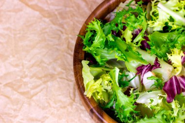 Çiğ organik salata yapraklarının farklı karışımının üst görüntüsü: marul, turşu, roket ahşap kasede hafif arka planda yemek için..