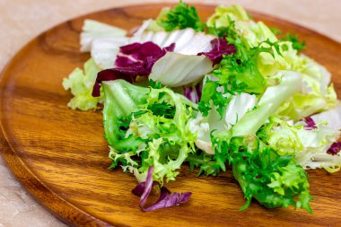 Çiğ organik salata yapraklarının farklı bir karışımı: marul, radicchio, ahşap tahtada roket hafif arka planda yemek için.