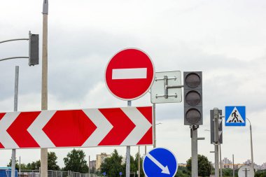 Kırmızı ve beyaz girmeyin ve gri renksiz bulutlu gökyüzü arkaplanındaki diğer işaretler.