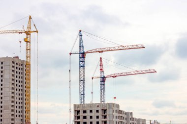 İnşaat alanında, yüksek vinç şehirde gri bloklu bir ev inşa ediyor..