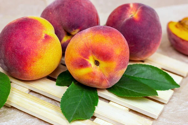 Fresh juicy red, yellow and orange peaches on light wooden table background in summer season.