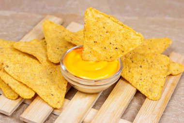 Sarı, tuzlu, çıtır çıtır ve gevrek üçgen Meksika mısır cipsleri. Hafif ahşap arka planda soslu..