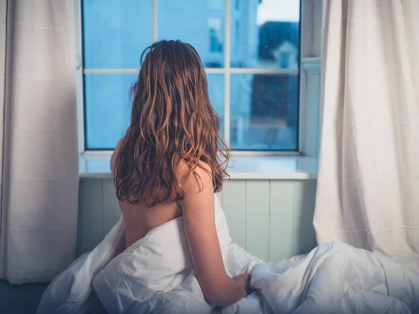 一个年轻的女人早上在窗前醒来 — 图库照片