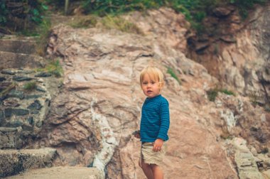 Küçük bir yürümeye başlayan bir uçurum tarafından duruyor