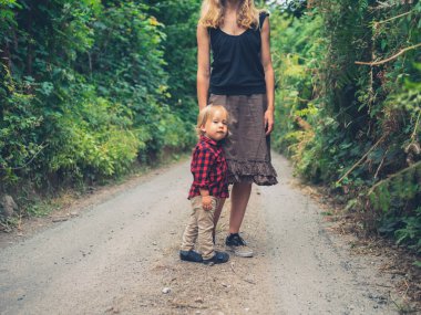 Genç bir anne ve onu yürümeye başlayan çocuk ormanda yürüyor