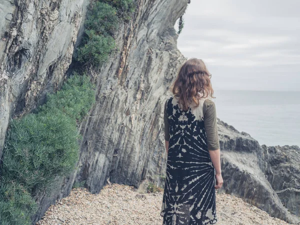 若い女性の海岸にいくつかの岩の上に立つと海を見ています — ストック写真