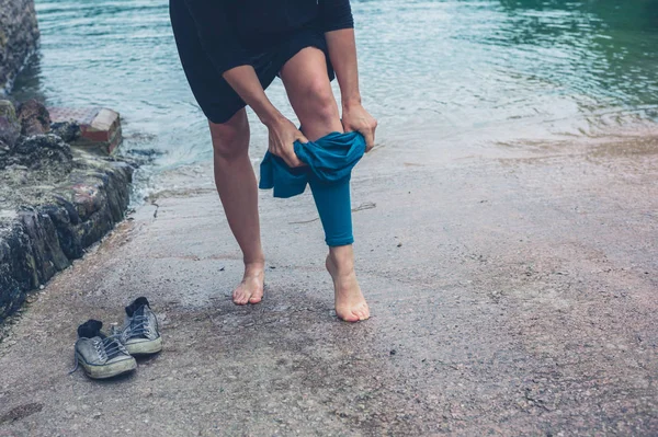 一位年轻女子在河里散步后 正在穿上裤子和鞋子 — 图库照片