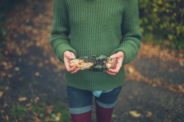 一个年轻的女人拿着一根小圆木站在大自然中 — 图库照片