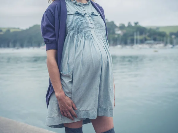 在一个海滨小镇上 一个年轻的孕妇站在河边 — 图库照片
