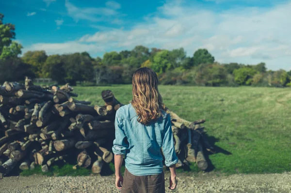 Een Jonge Vrouw Staat Door Een Stapel Van Logboeken Het — Stockfoto