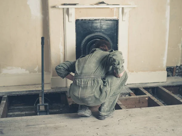 一个穿着锅炉服的年轻女子正在维多利亚时代的房子里检查壁炉 — 图库照片