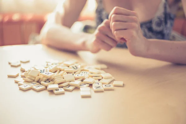 若い女性は 単語ゲームの手紙の束をテーブルに座って — ストック写真