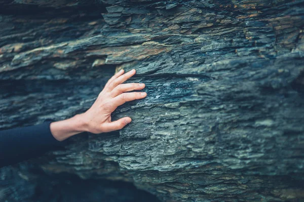 一个年轻女子触摸岩石表面的手 — 图库照片