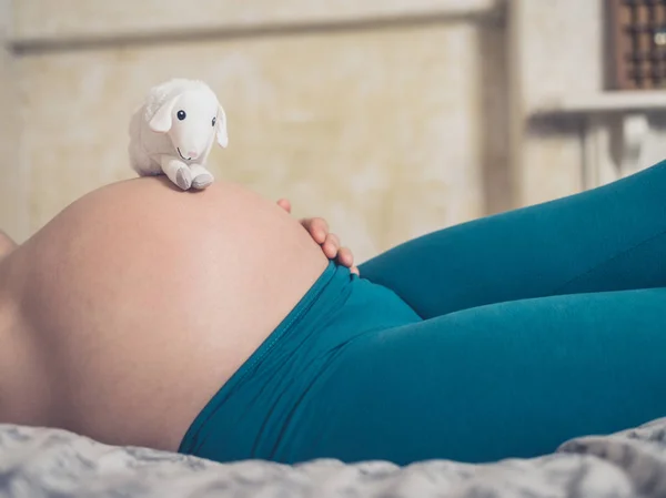 Uma Mulher Grávida Está Deitada Cama Com Uma Ovelha Pelúcia — Fotografia de Stock