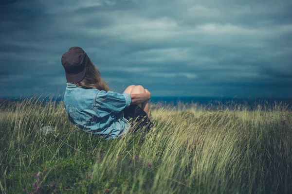 Ung Kvinna Sitter Ett Fält Blåsig Dag — Stockfoto