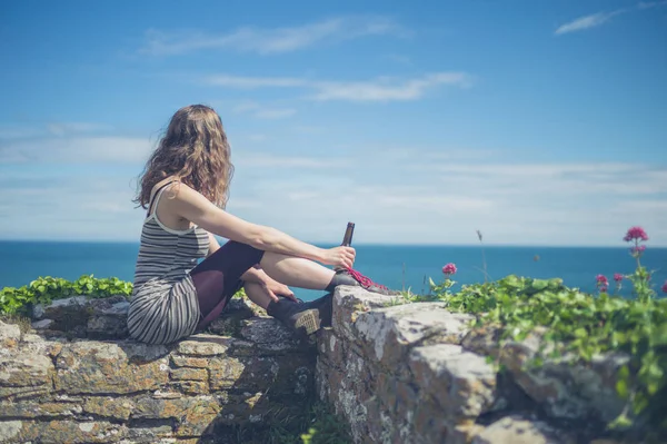 Una Joven Está Sentada Una Pared Junto Mar Día Verano — Foto de Stock