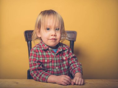 Küçük bir yürümeye başlayan çocuk bir masada oturuyor
