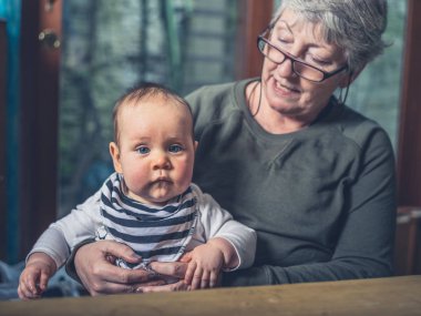 Bir Büyükanne onu bebek torun ile bir yemek masada oturuyor