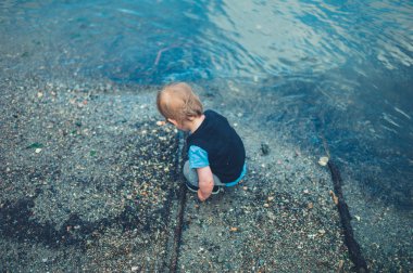 Küçük şirin bir yürümeye başlayan çocuk su ile oynuyor