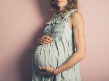 Pembe bir arka plan karşı genç bir hamile kadın